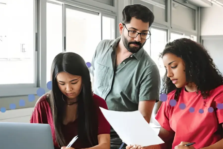 Group of young professionals collaborating on documents and laptop in modern office