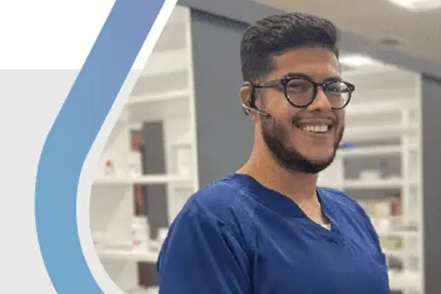 Smiling healthcare professional in blue scrubs with headset working in pharmacy