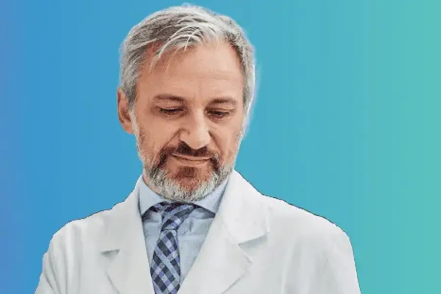 Experienced male doctor in white coat with tie looking down against blue background