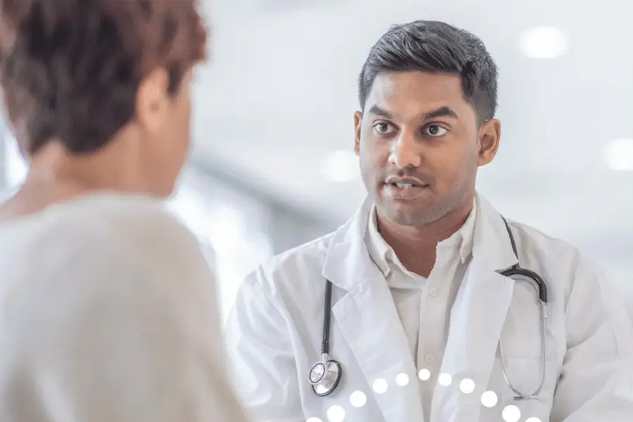 Doctor in white coat with stethoscope talking to patient during medical consultation