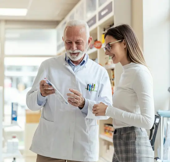 Pharmacist consulting with a female customer inside a pharmacy about prescription medication.
