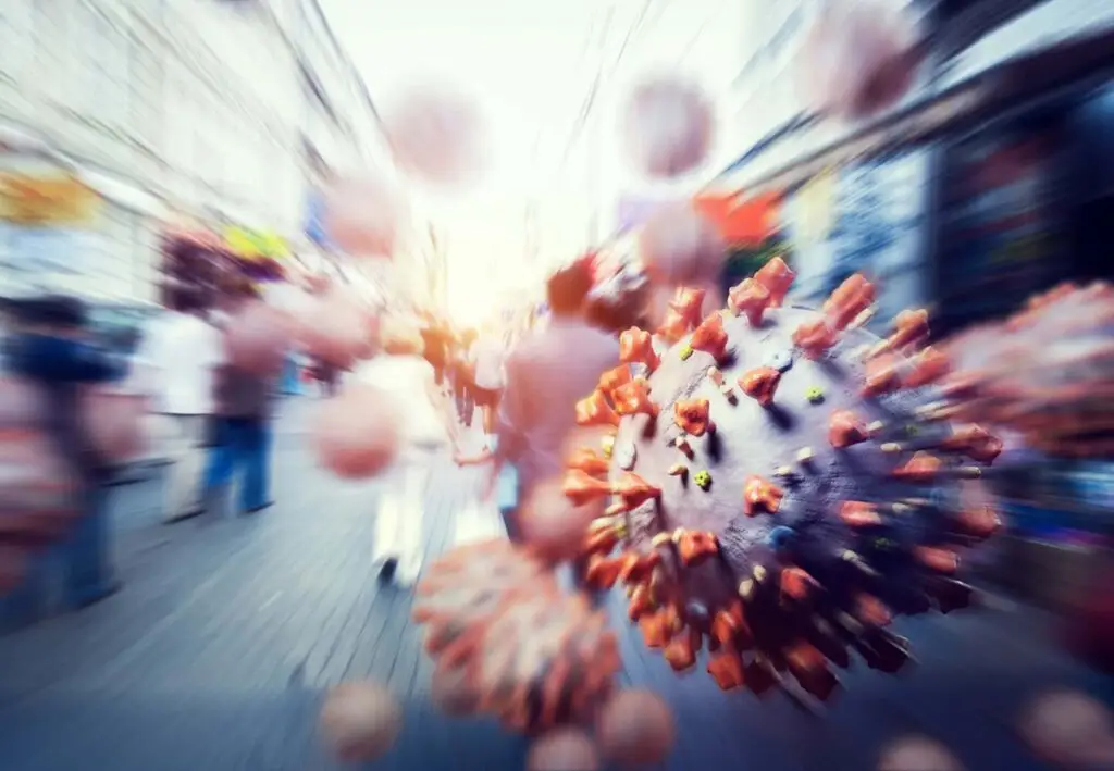 Illustration of coronavirus particles spreading in a busy city street with blurred crowds in the background.