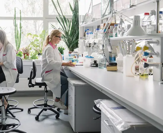 Scientist working in a modern laboratory with lab equipment and plants by the window.