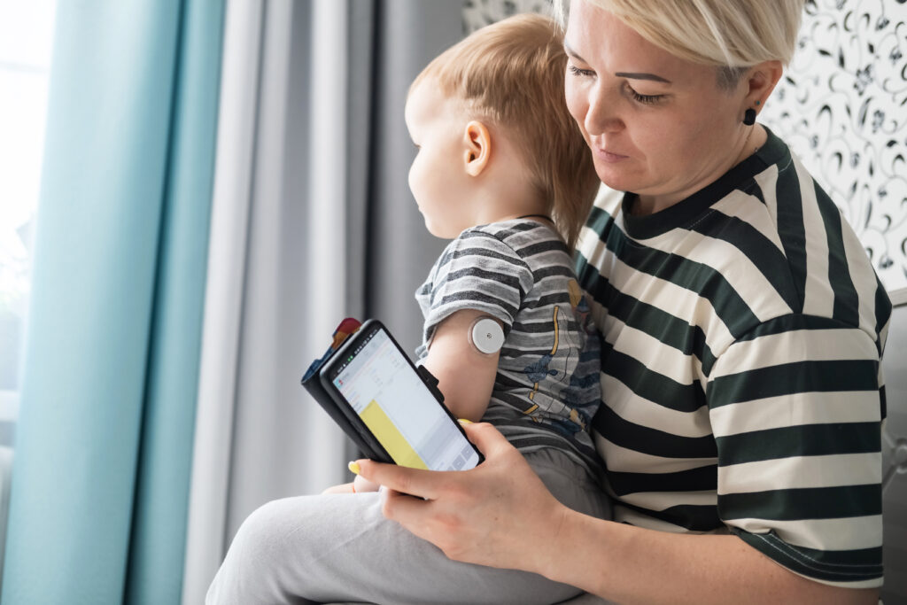 Mother holding child and monitoring remotely