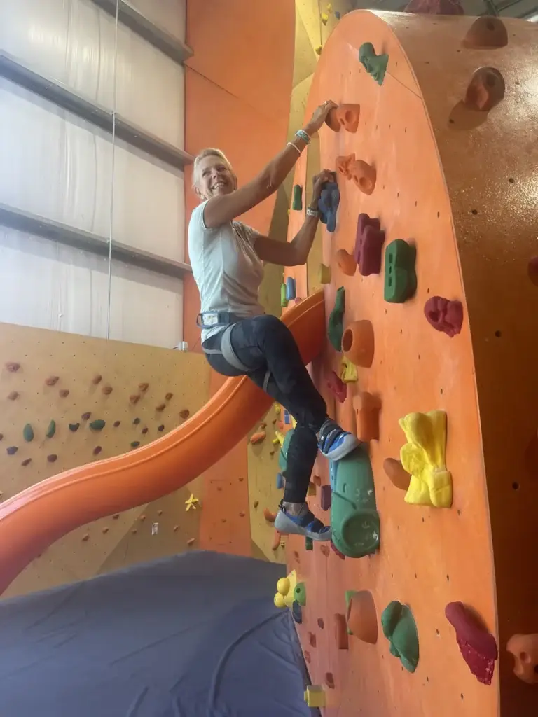 Laura rock climbing on a colorful indoor bouldering wall